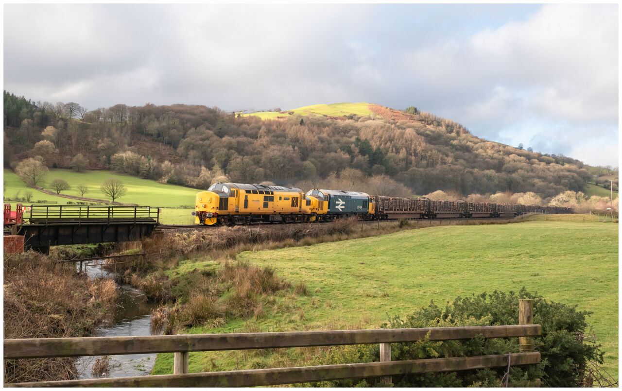 Cambrian EE's
97303 with 37424 working 6C56, the 09.50 Aberystwyth Krono Colas to Chirk Kronospan Colas Rail on The Cambrian Line approaching Carno, Saturday 17.1.26 A couple of poles with wires removed from this image, along with a poor old dead sheep floating in the stream.
