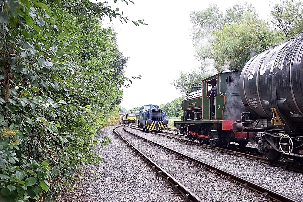 Piggy in the middle
The interchange yard at Preston sees the incoming service from Lindsey Docks arrive behind Class 60 60096 whilst the outgoing empties are headed by Bagnall 2680 Courageous and Sentinel 10282, providing air-braking, waits to shunt the incoming service for the steam locomotive to work forward to the discharge siding.
