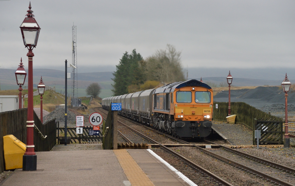 The climber
Class 66/7 66728 Institution of Railway Operators climbs through Ribblehead on October 28th 2021 whilst working an Arrow Quarry - Bredbury service which was en route to Blea Moor to reverse prior to continuing to Bradbury.

Date  :  28/10/21
Loco  :  66728 Institution of Railway Operators
Location  :  Ribblehead
Working  :  Arcow Quarry - Bredbury en route to Blea Moor for reversal
