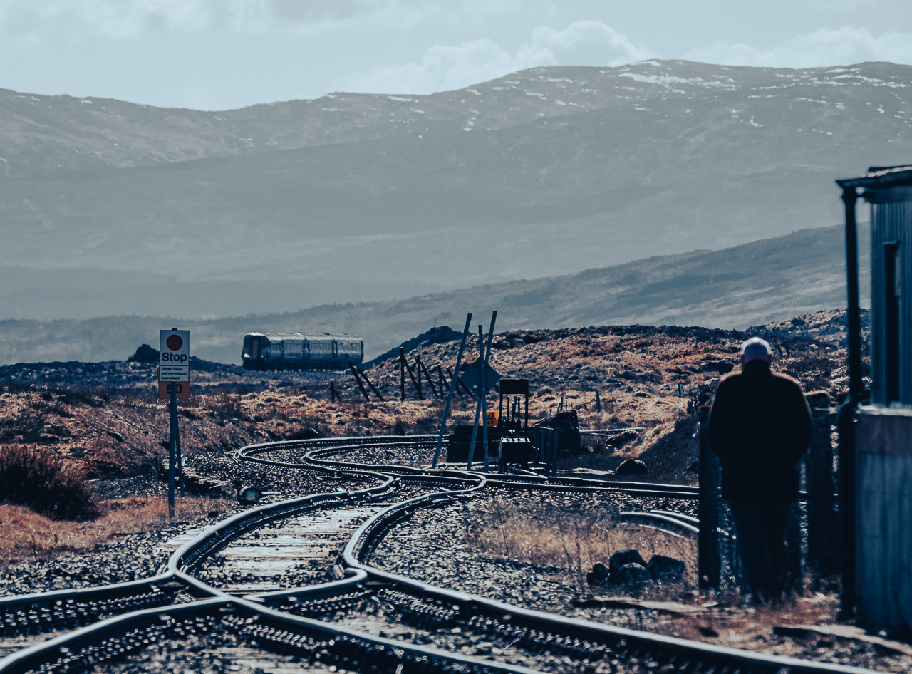 Watching and Waiting
The station building and signal box are rented accommodation and a current resident stands watching as ScotRail Class 156 Nos. 156474 & 156477 approach Corrour with 1Y41, the 08:21 Glasgow Queen Street – Mallaig service on 19th April 2023.
