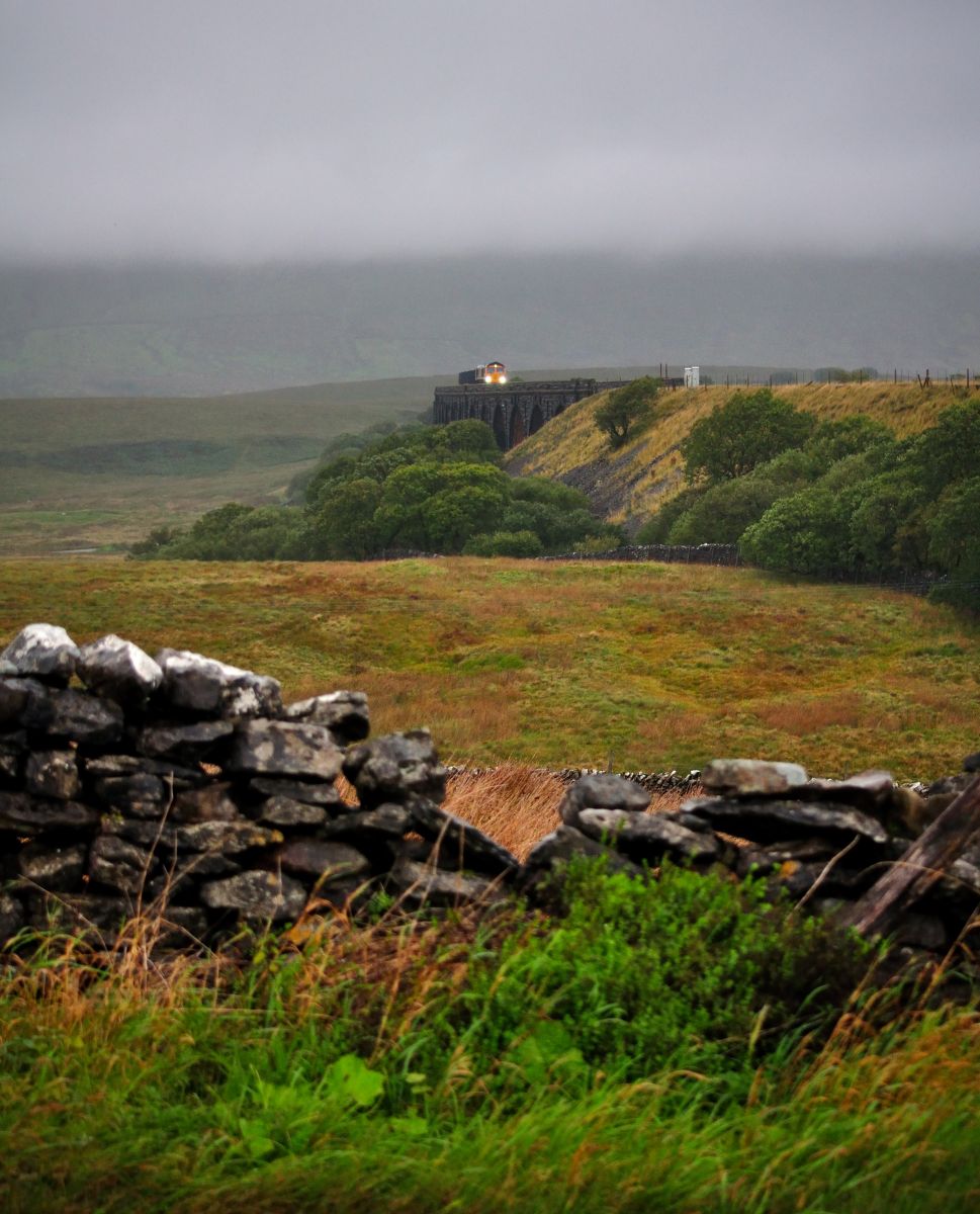 Looming out of the Gloom
With Ribblehead and Whernside shrouded in thick grey cloud, the headlights of a GBRf class 66 pierce through the gloom as it crosses the viaduct with a Horton Quarry to Tuebrook Sidings train on 10/9/2026.
Keywords: Class66; GBRf; Settle&Carlisle; Ribblehead; Whernside