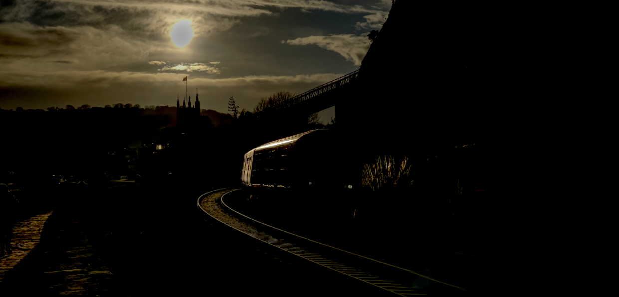 Out Of The Sun
150239 starts its run along the sea wall at Teignmouth with the 2F23 1441 Paignton to Exmouth. Shooting directly into the sun is always a challenging activity but having observed a few earlier trains I saw there was a glint developing and I also liked the backlit campus grass. 
I deliberately left the dead space in front of the train in the shot as I liked this format for the shot.
