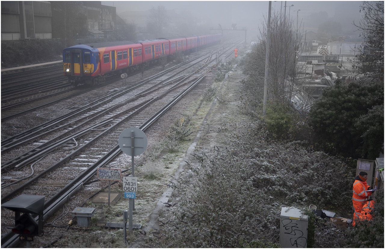 Wimbledon West Fog
5701 (Class 455/7) at Wimbledon West on the 11:32 Waterloo - Epsom. Signal Engineers work in the freezing fog at a lineside cabinet.
