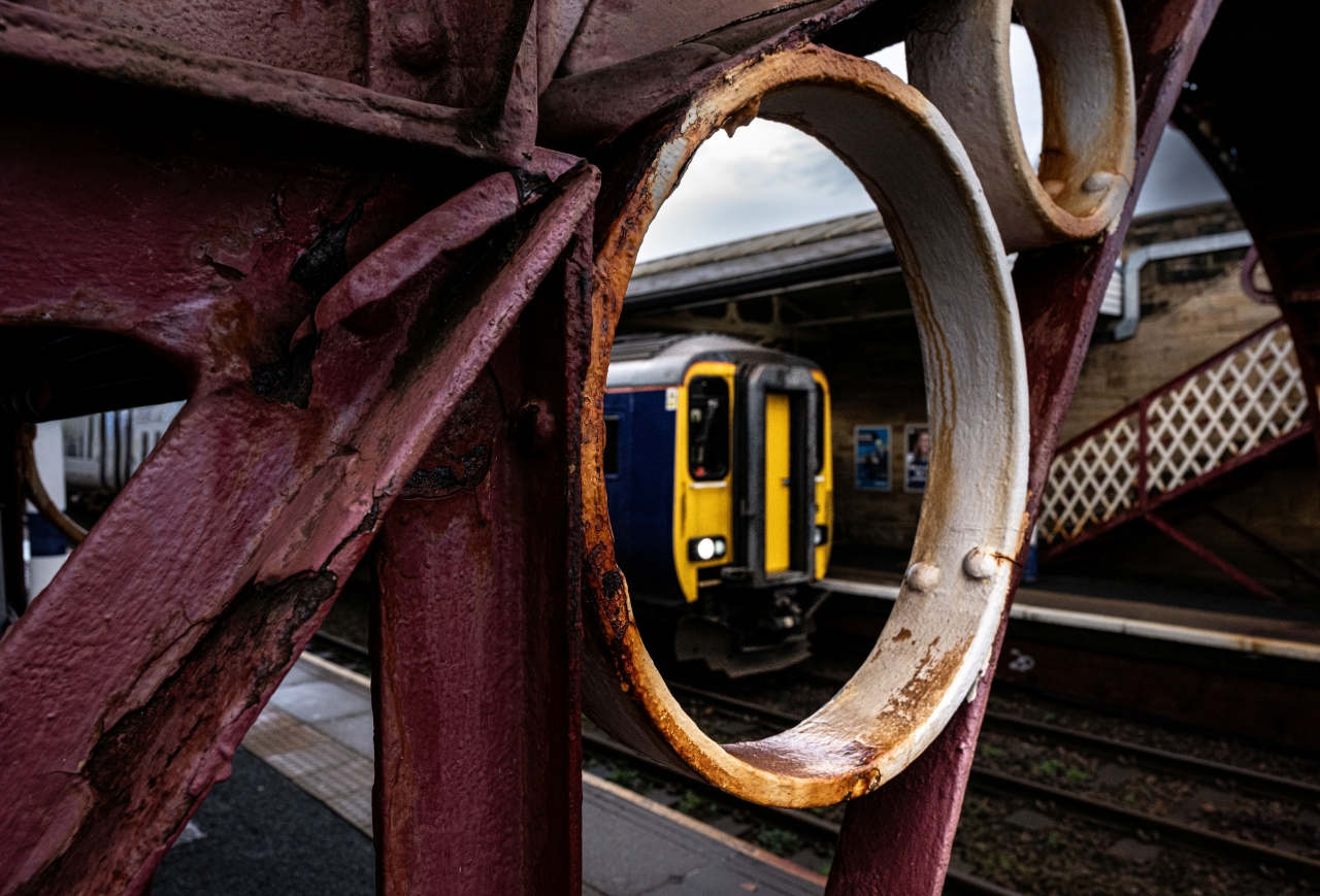 'Through the Round Window' 
Newcastle bound 156465 waits time at Hexham and is captured through ironwork of the NER built footbridge at Hexham.
